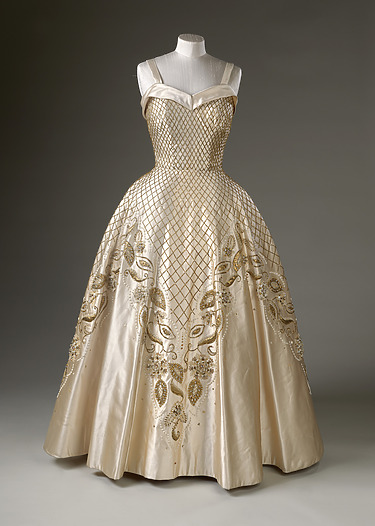 Elegant vintage ball gown with intricate gold embroidery and a fitted bodice displayed on a mannequin.