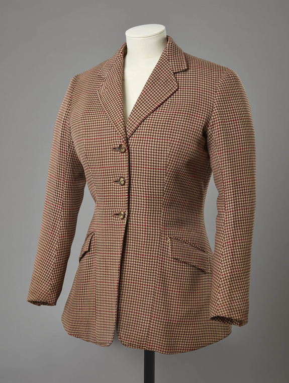 Brown and red houndstooth blazer on a mannequin against a gray background.