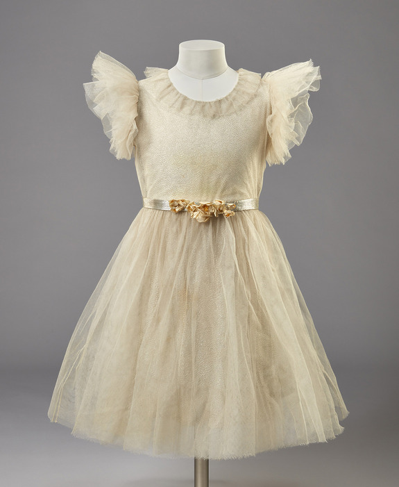 Vintage-style ivory dress with tulle layers, ruffled sleeves, and a floral sash displayed on a mannequin.