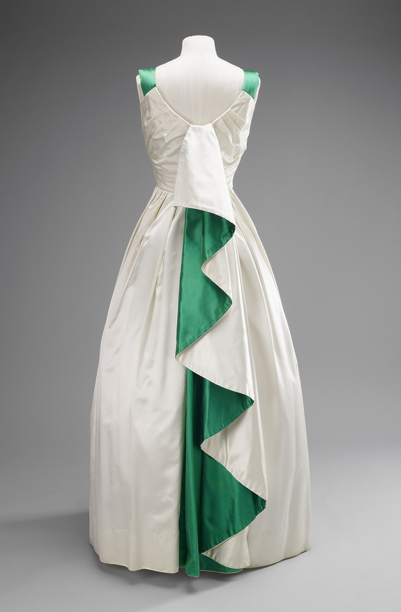 Vintage white evening gown with green zigzag detail down the back, displayed on a mannequin against a gray background.