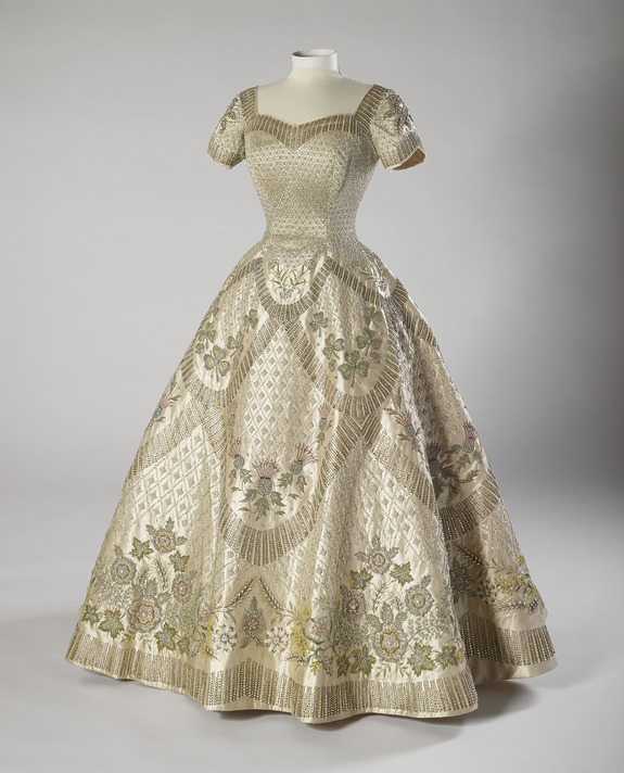Elegant vintage gown with intricate floral embroidery and fitted bodice displayed on a mannequin against a neutral background.