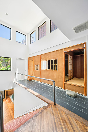 Modern interior with a Japanese-style room, tatami mats, and shoji screens, featuring large windows and sleek flooring.
