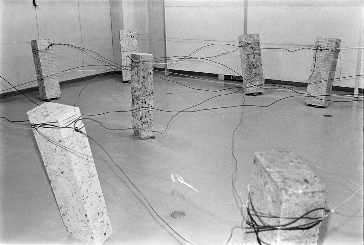 Abstract art installation with stone pillars interconnected by wires in a spacious room.