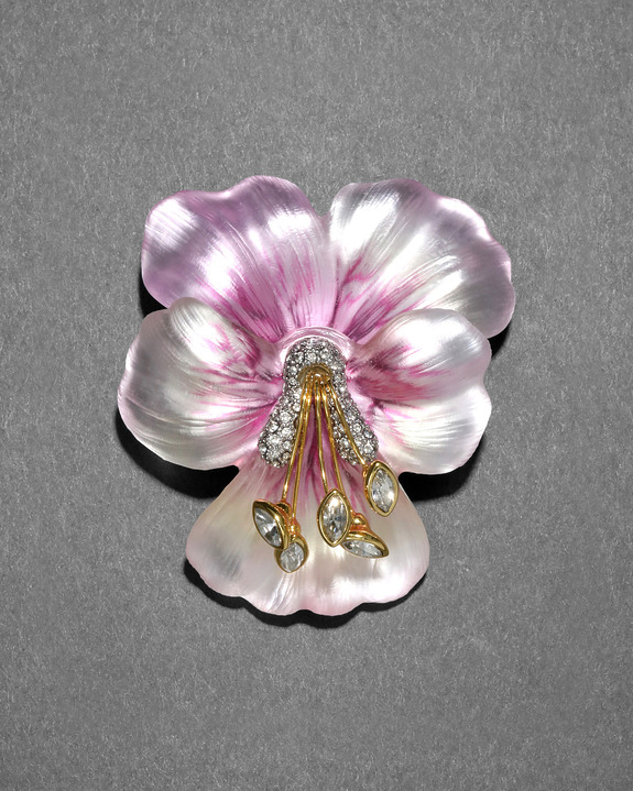 Purple and white flower-shaped brooch with diamond accents on a gray background