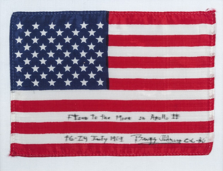 American flag with handwritten text: "Flown to the Moon on Apollo 11, 16-24 July 1969, Buzz Aldrin."