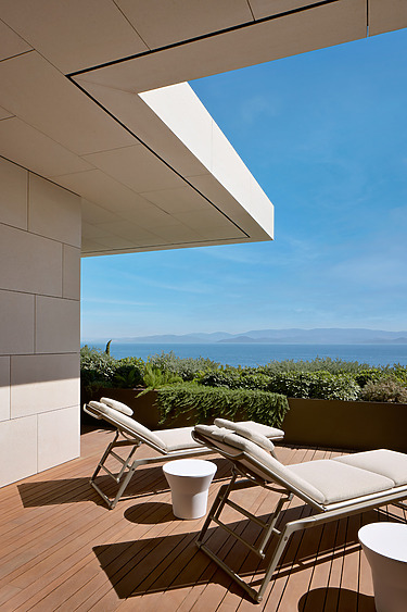 Two lounge chairs on a modern terrace with ocean view under a clear blue sky