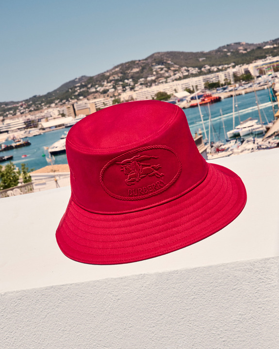 Red bucket hat on a white ledge with marina and hills in the background under a clear blue sky.