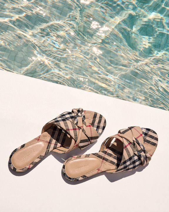 Checkered sandals on white surface near swimming pool reflecting sunlight.