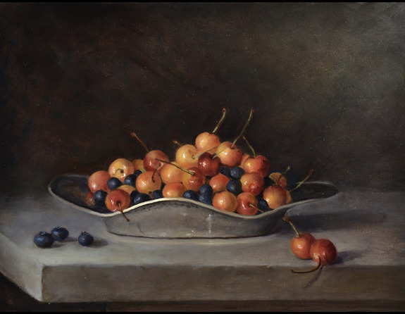 Bowl of cherries and blueberries on a table, with some fruits scattered on the side against a dark background.