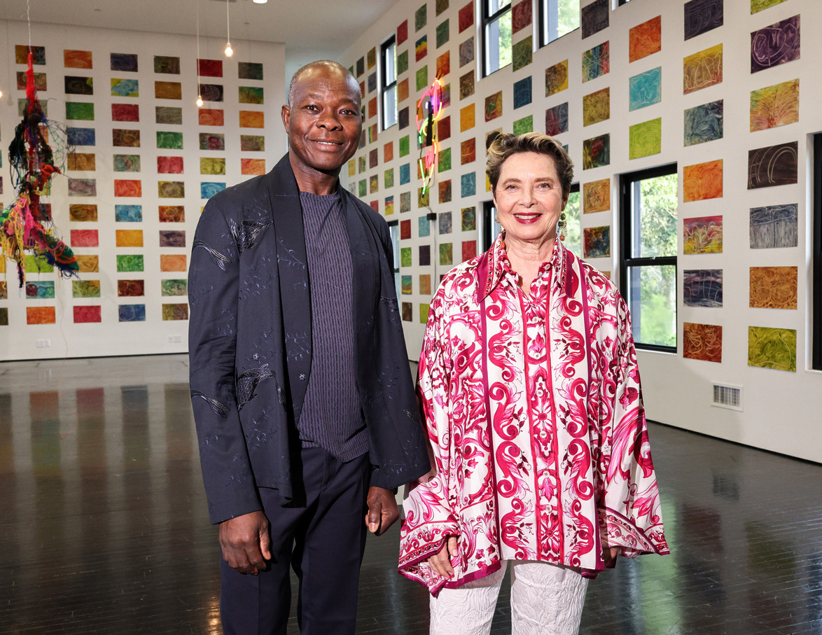 Two people standing in an art gallery with colorful abstract paintings on the walls.