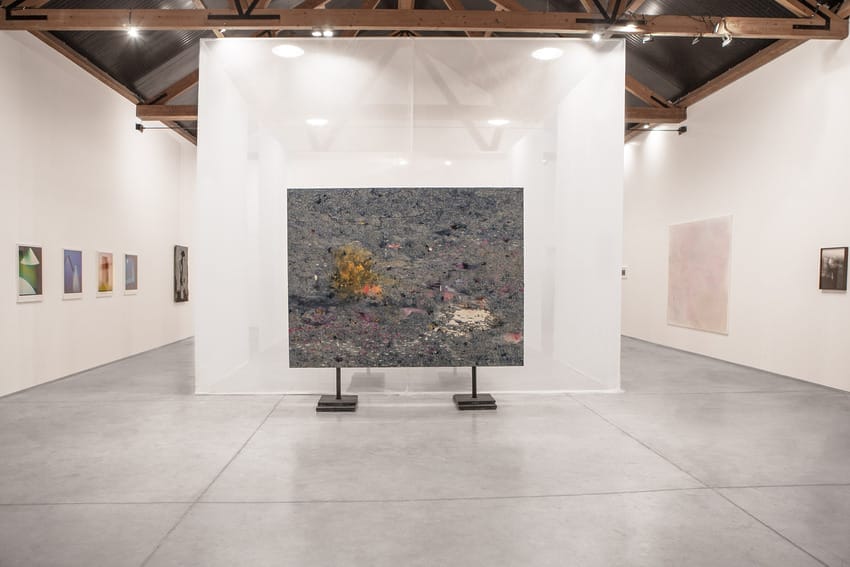 Modern art gallery interior with contemporary paintings on white walls, central large abstract artwork, and industrial ceiling.