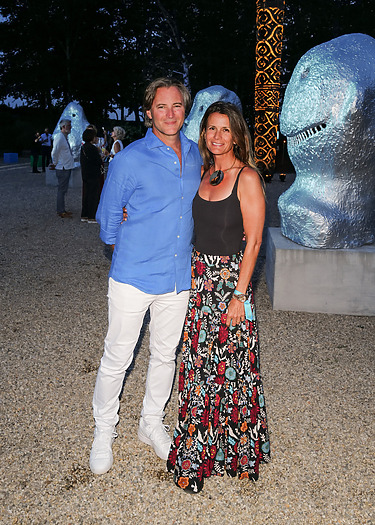 A couple posing in a park with large modern sculptures and people in the background