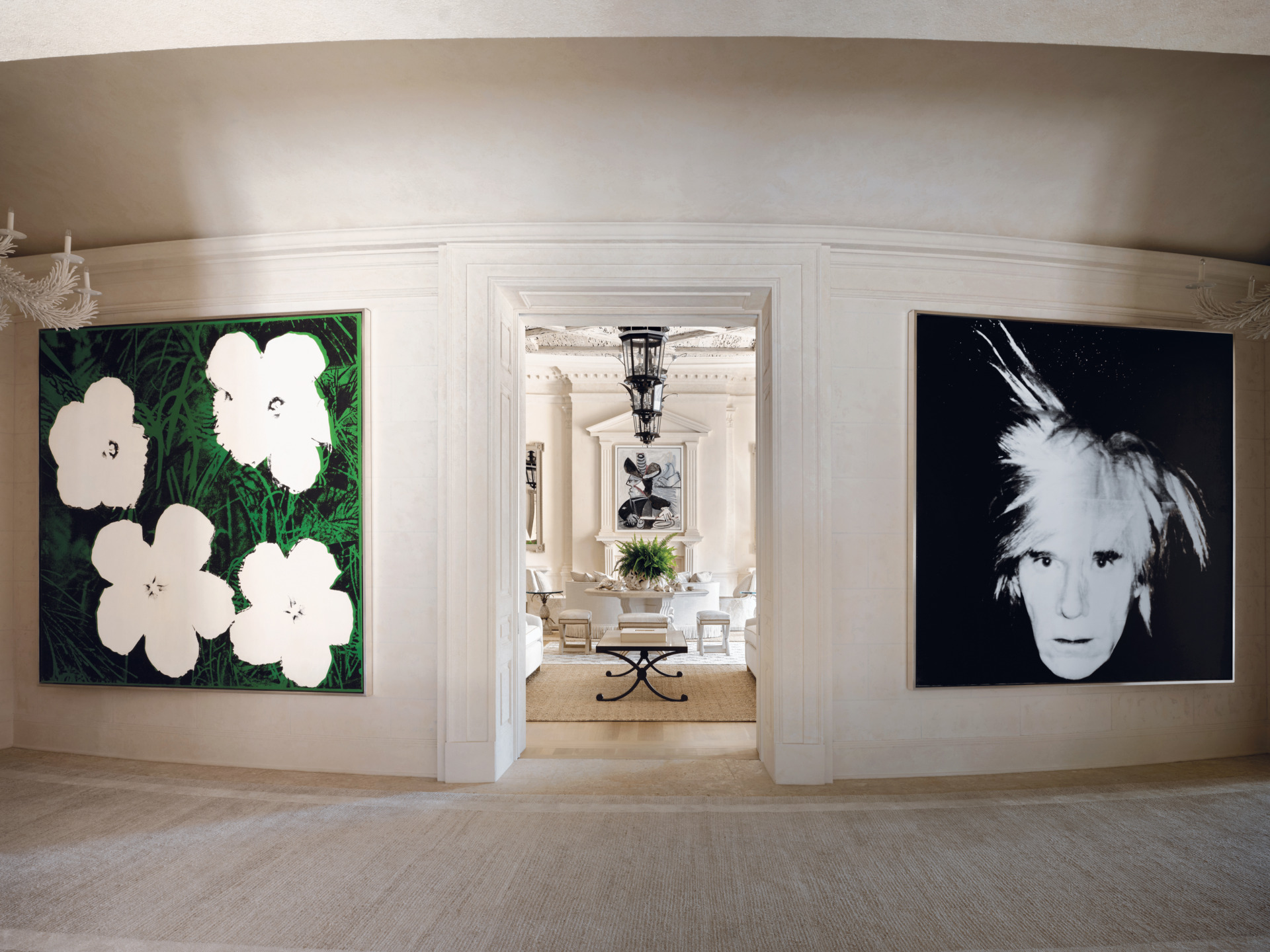 Interior with large floral painting and portrait on walls, classic decor, chandelier, and white furniture in elegant room.