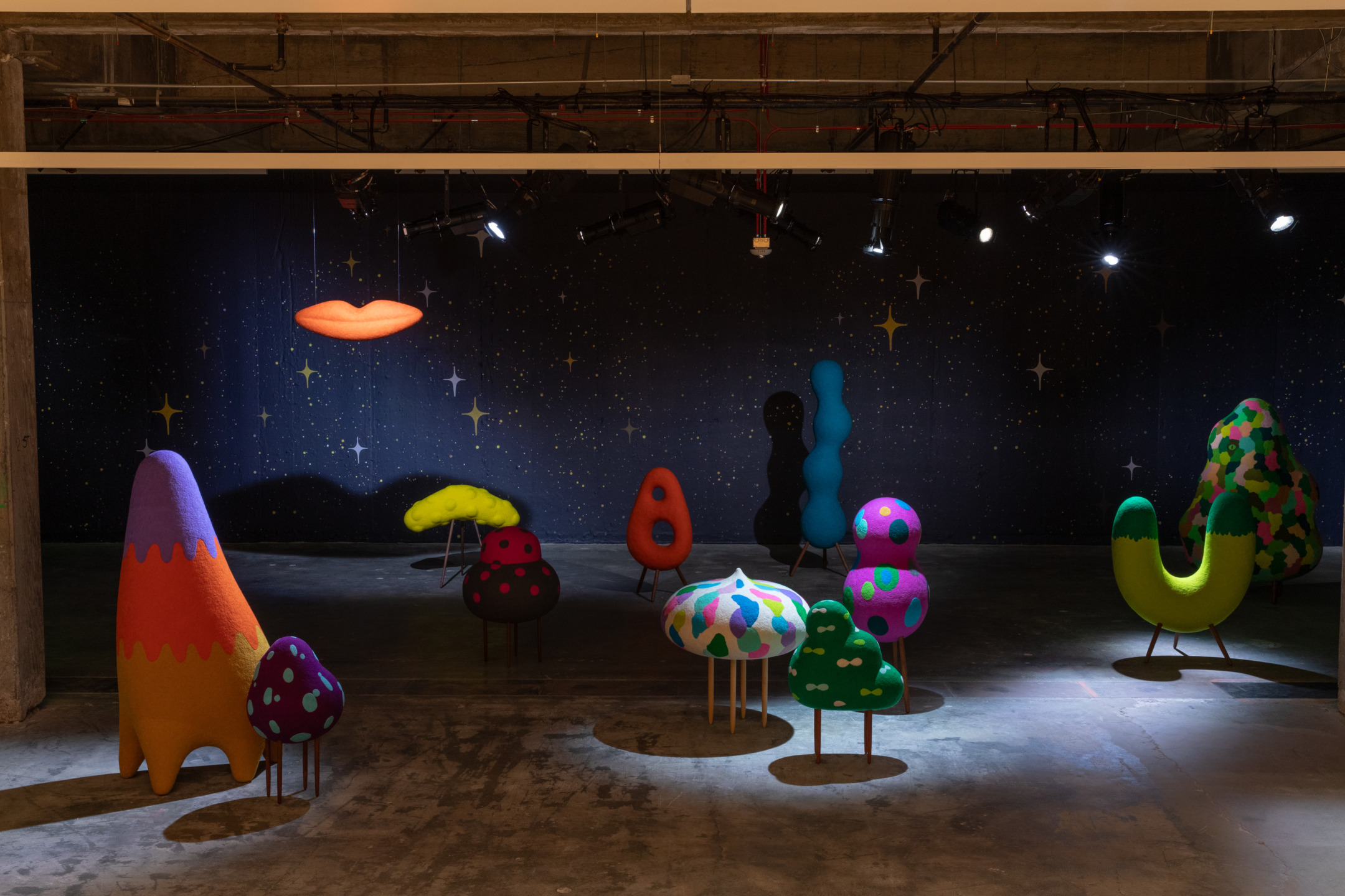 Colorful, abstract sculptures in a dimly lit gallery with a starry backdrop creating a whimsical and imaginative scene.