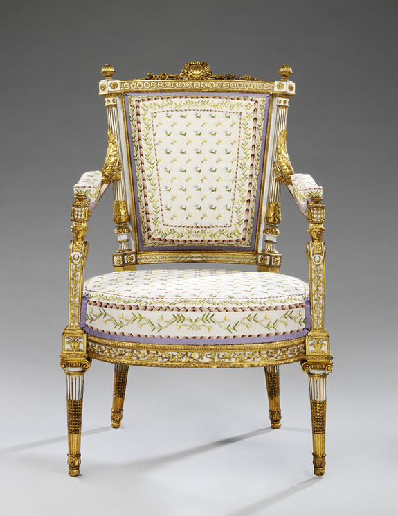 Ornate antique chair with gold accents, floral upholstery, and intricate carved details displayed on a neutral background.