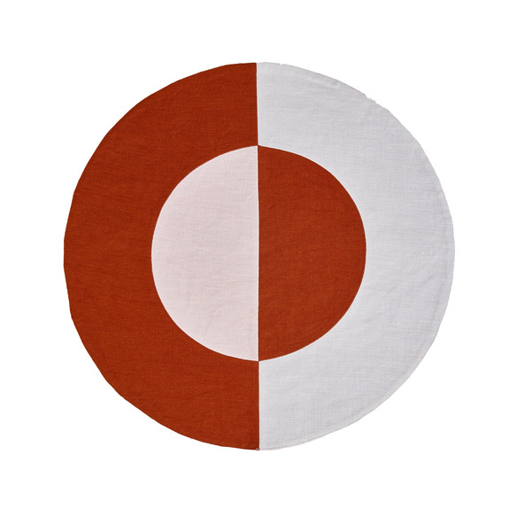 Round rug with geometric design in red, white, and pink sections.