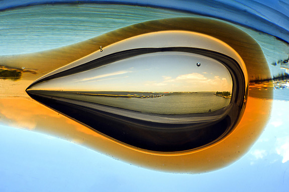 Reflection of a seascape in a drop of water with sky and horizon blending into abstract colors.