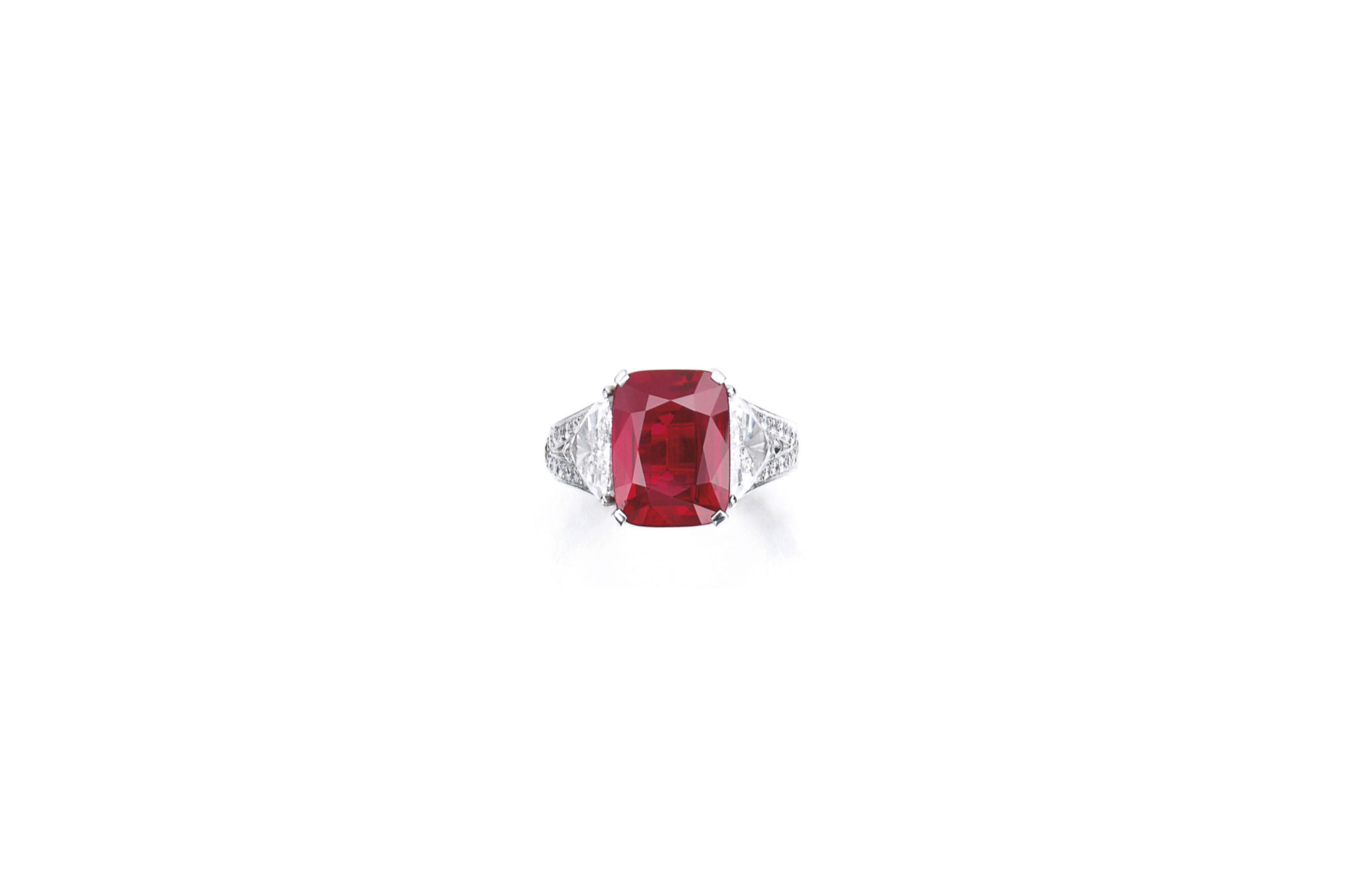 Red gem-studded ring with intricate design and diamond accents on a white background.