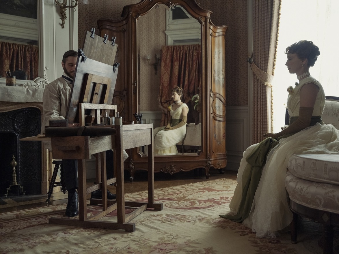 Artist painting a woman in a Victorian-era room with a mirror reflecting the scene