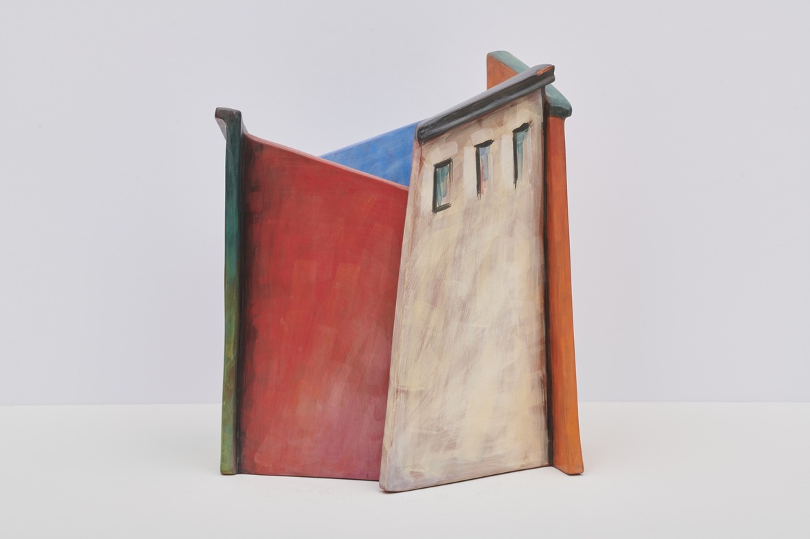 Colorful abstract sculpture with geometric shapes and vibrant hues on a plain background.