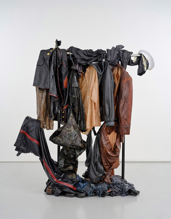 A collection of various leather and fabric clothing arranged artistically on a stand against a plain background.