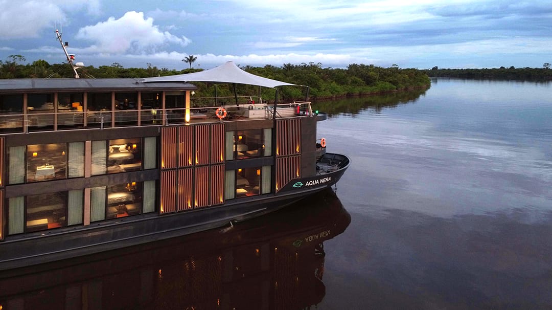 luxury riverboat cruising on a calm river surrounded by lush greenery and a partly cloudy sky