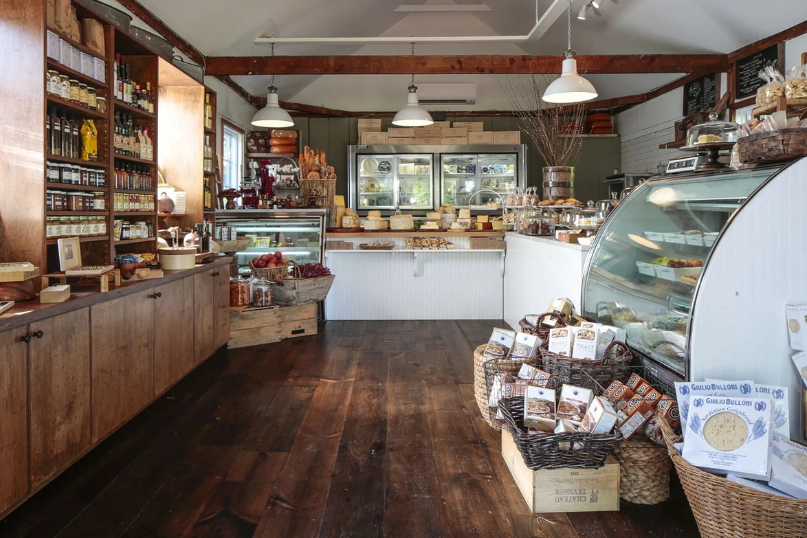 Interior of a rustic grocery store with wooden shelves, fresh produce, and a variety of packaged goods displayed.