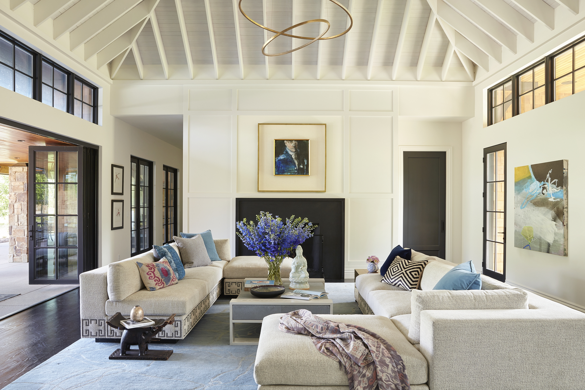 Modern living room with two beige sofas, a black fireplace, blue rug, and decorative artwork on the walls.