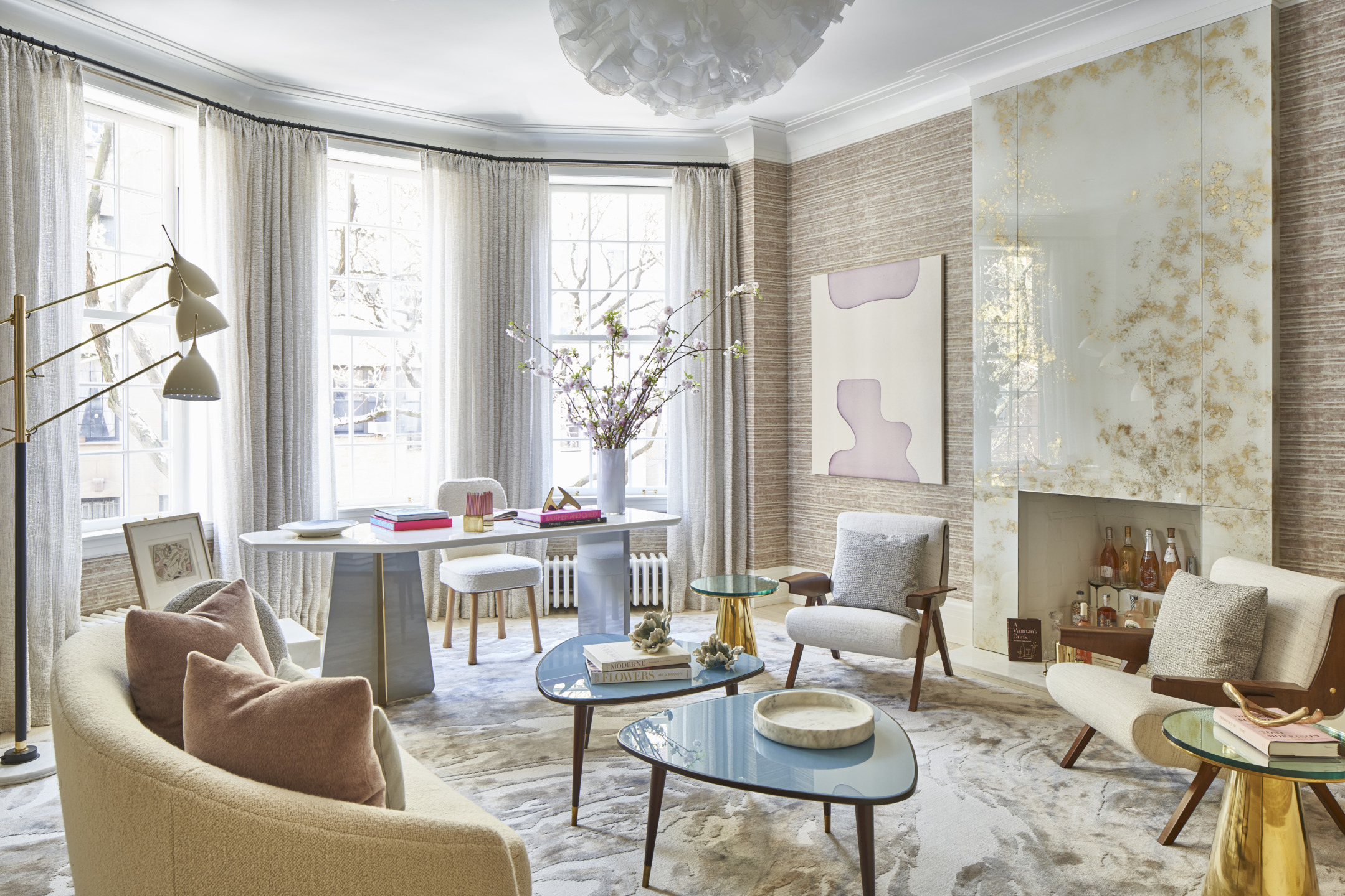 Elegant modern living room with curved sofa, glass coffee tables, soft lighting, large windows, and stylish decor.