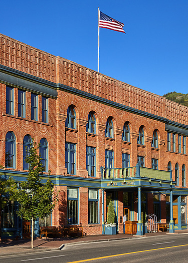 Historic red brick hotel with arched windows and American flag against clear blue sky.