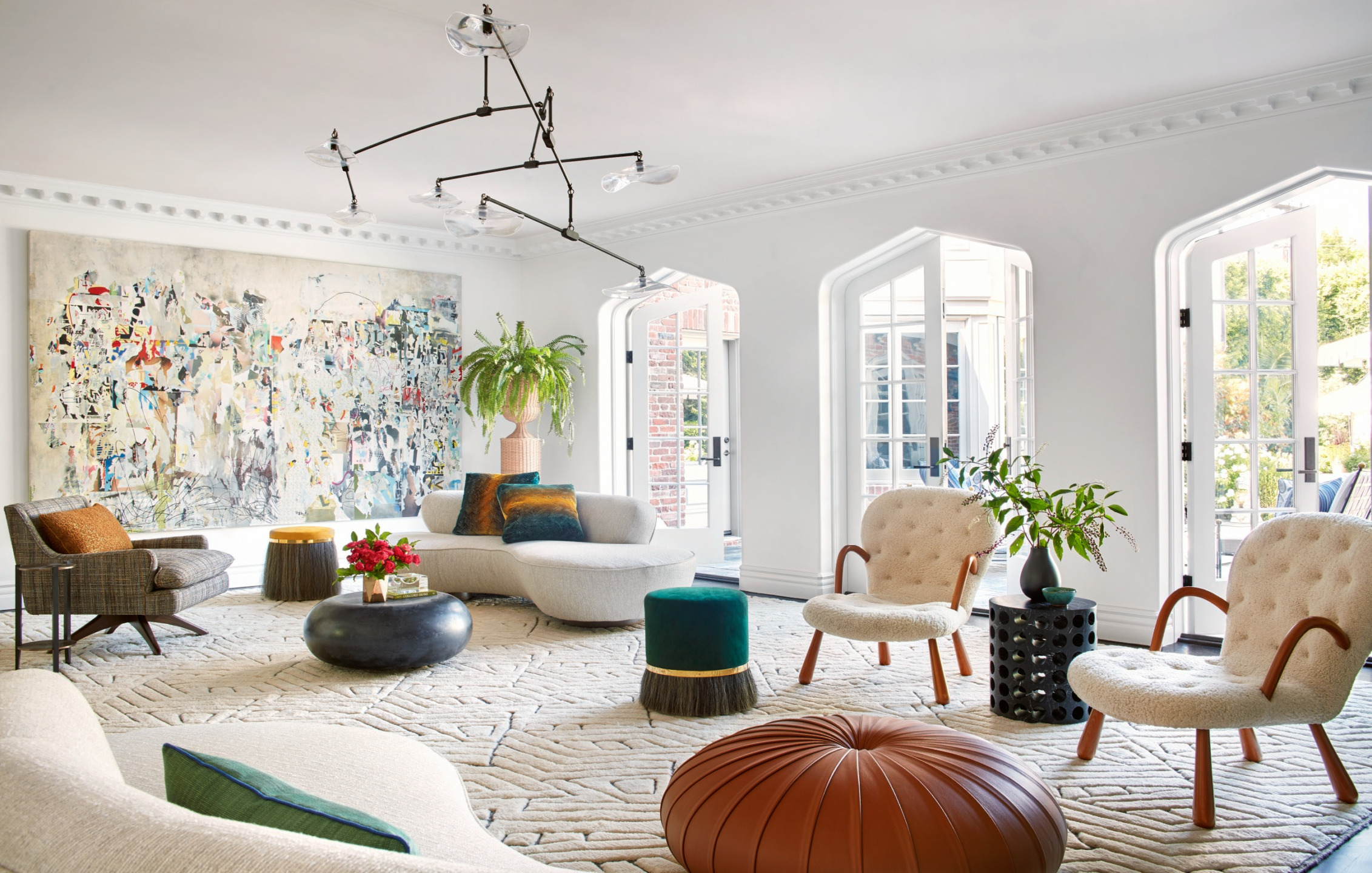 Modern living room with abstract art, white sofas, stylish chairs, and large windows letting in natural light.