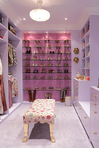 Lavish walk-in closet with light purple walls, shoe display, clothing racks, and polka-dot bench in the center.