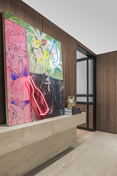 Modern art piece with neon elements on a wooden-paneled wall, featuring flowers and abstract shapes in a contemporary room.