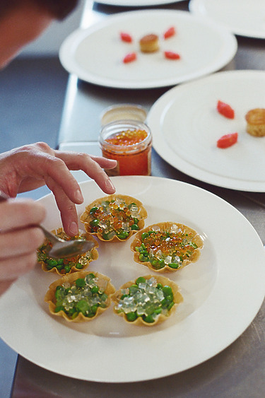 Chef garnishing gourmet tarts with vibrant ingredients, adding detail and creativity to each dish on a white plate.