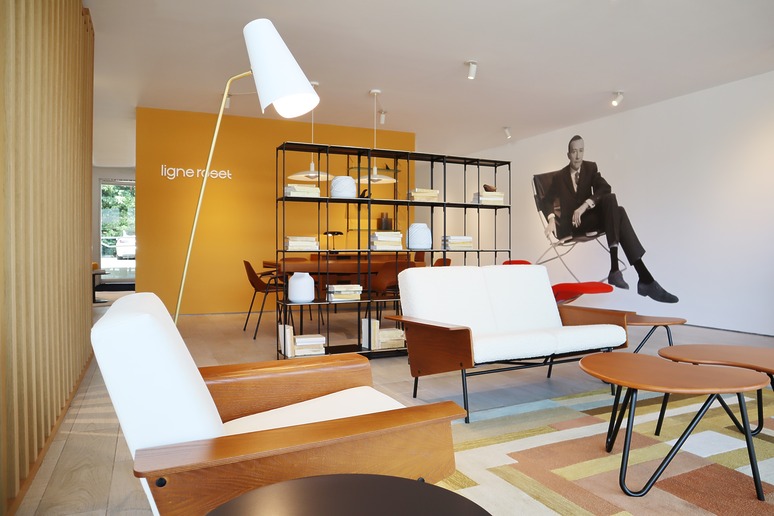Modern living room with stylish furniture, wooden accents, colorful rug, and a large wall art of a sitting man.