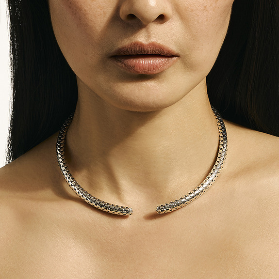 Woman wearing an open metallic choker with a patterned design on her neck.