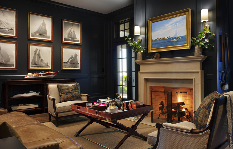 Cozy living room with a lit fireplace, dark walls, nautical decor, and a model ship on a shelf.