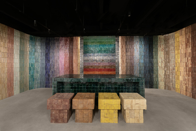 Colorful tiled room with a mosaic wall, square table, and four matching blocky stools in a modern architectural design.