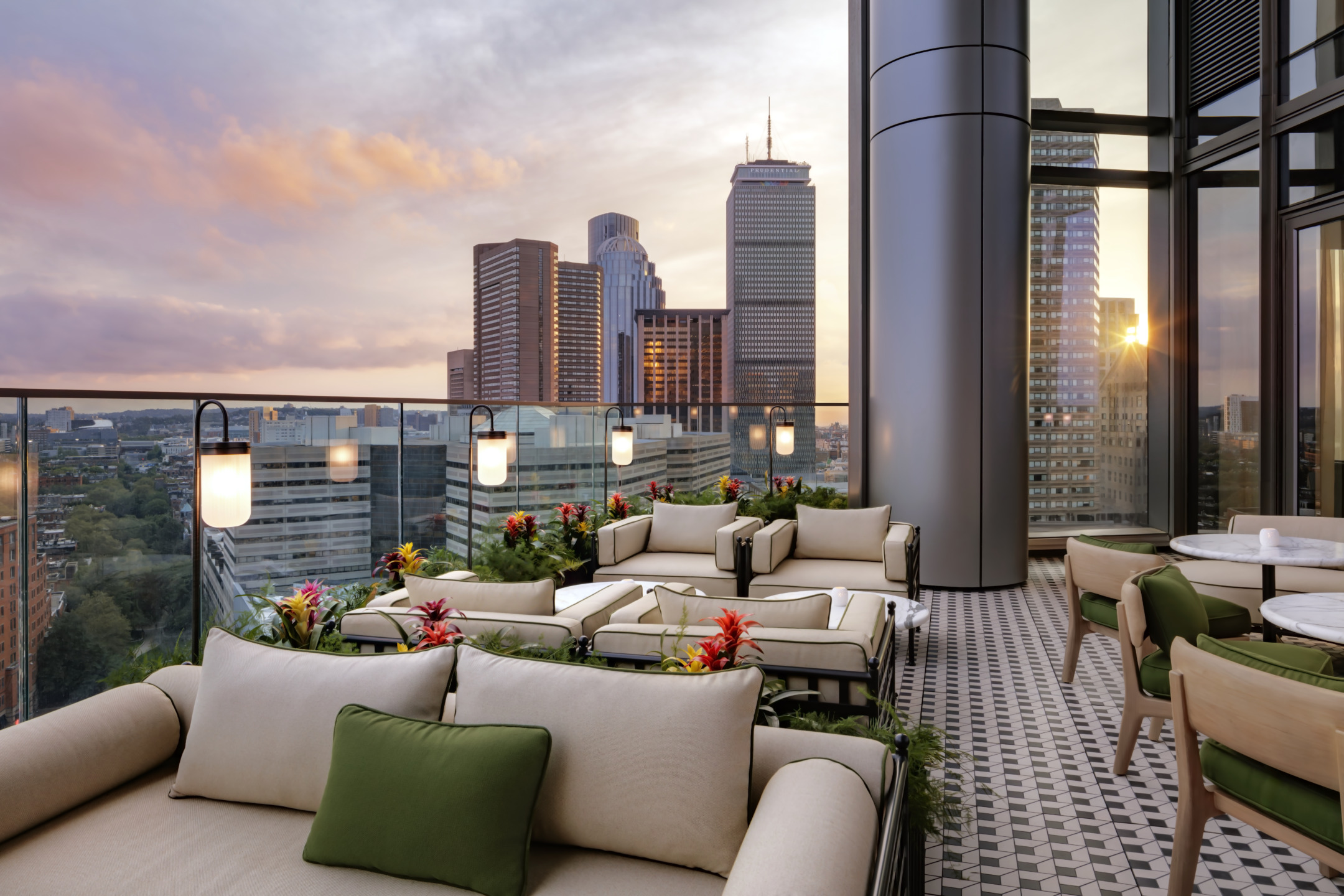 Rooftop lounge with modern seating, cityscape view, and sunset sky.