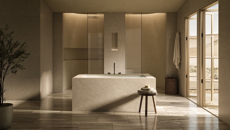 Minimalist bathroom with a central bathtub, natural lighting, wooden stool, towel, and potted plant next to a glass door.