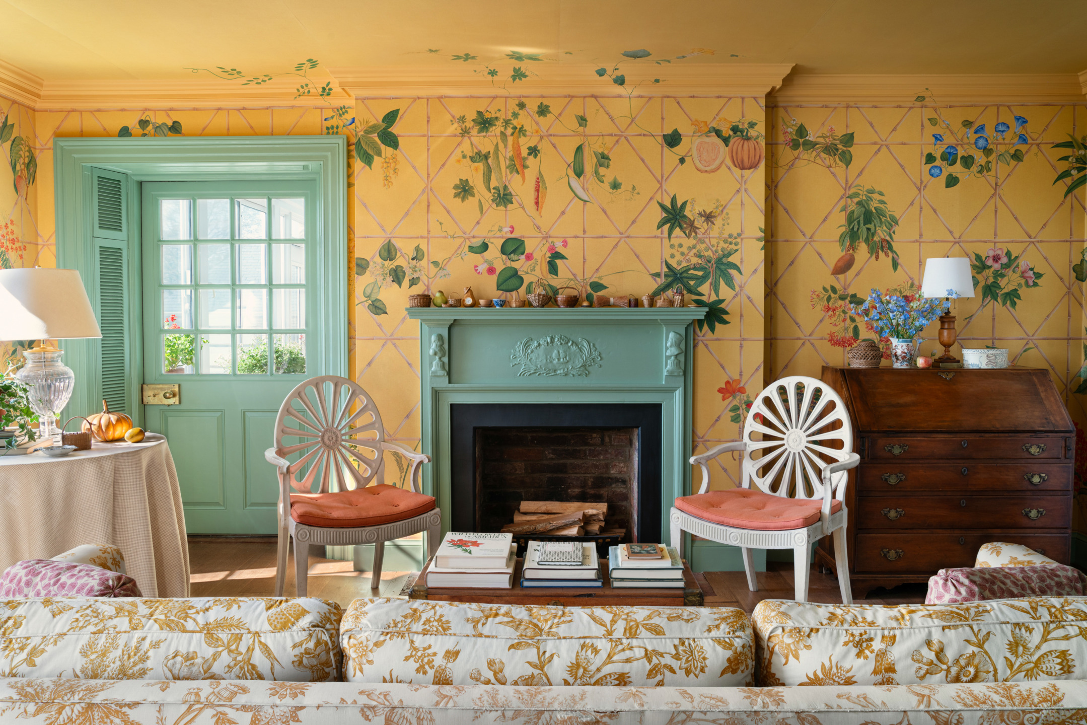 Colorful living room with floral wallpaper, vintage chairs, and a fireplace. Cozy and inviting interior design atmosphere.
