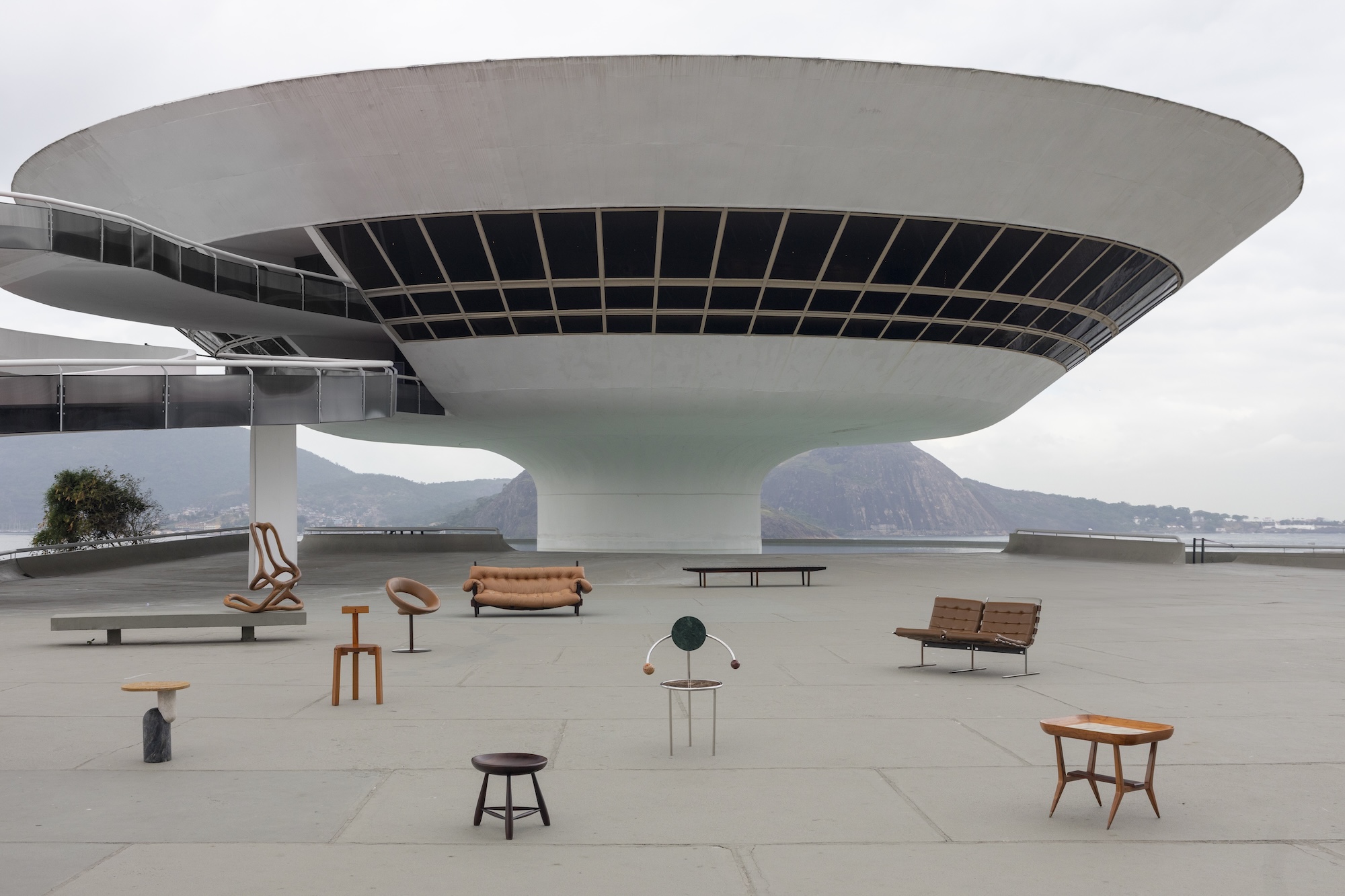 Modern art installations displayed outside a large, futuristic-style building with a panoramic view in the background.