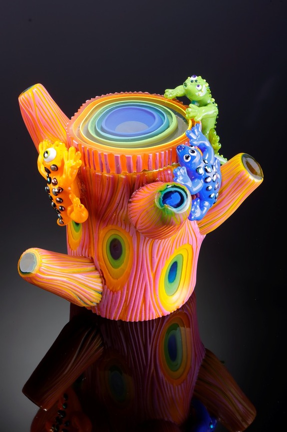 Colorful glass art piece with vibrant patterns and playful lizard designs on a reflective surface.