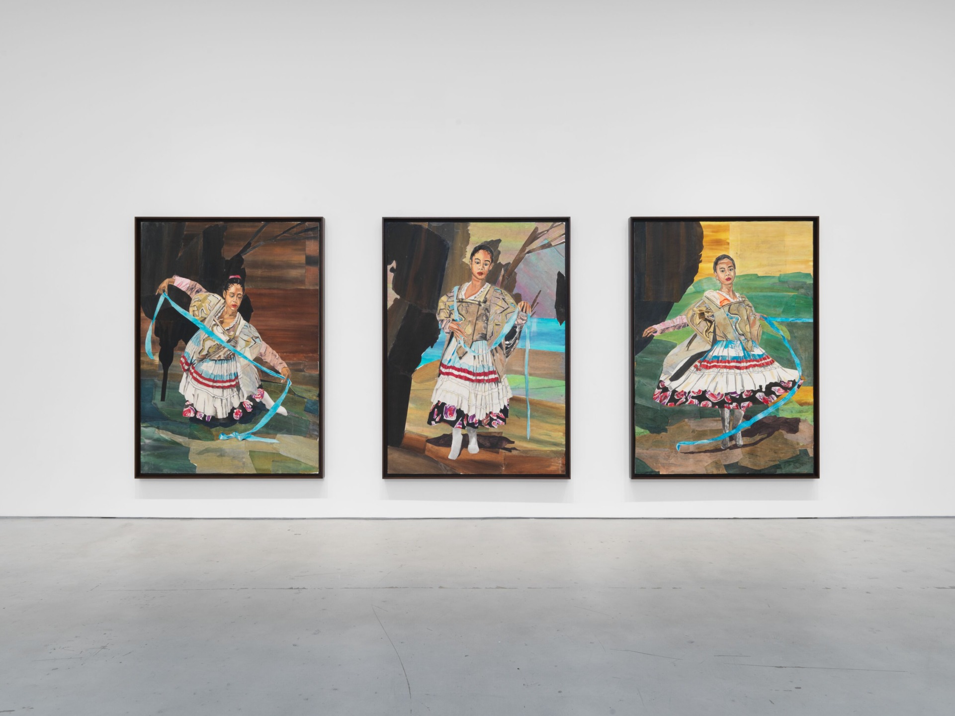 Three framed paintings of dancers in colorful attire displayed on a white wall in a gallery setting.