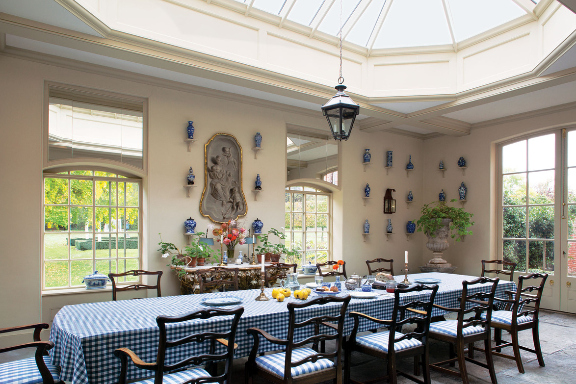 Elegant dining room with a skylight, decorated walls, long table set for dining, and a scenic garden view through windows.