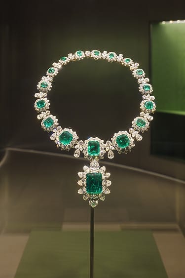 Emerald and diamond necklace on display, featuring large green emeralds surrounded by sparkling diamonds in an elegant setting.