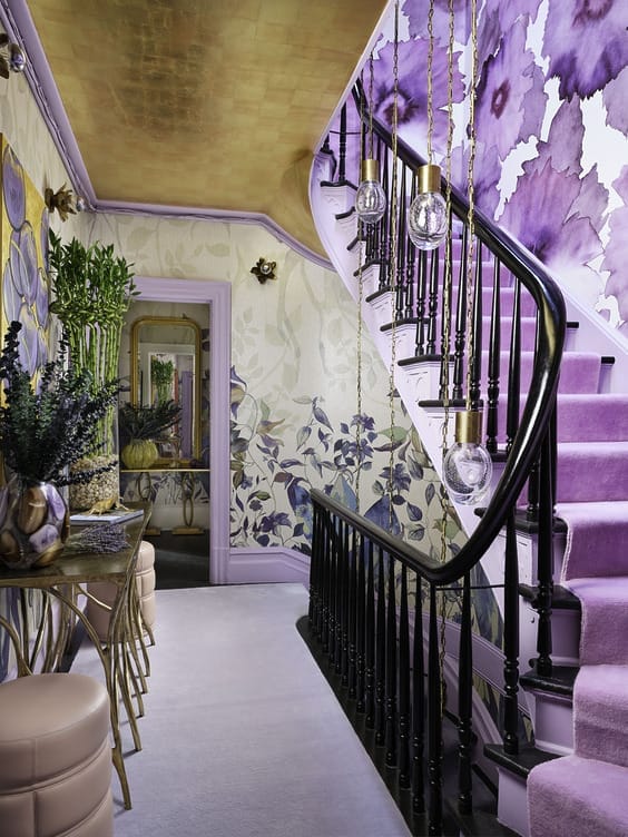Vibrant staircase with floral wall designs, pink carpet, black railing, and modern lighting fixtures in a stylish home interior.
