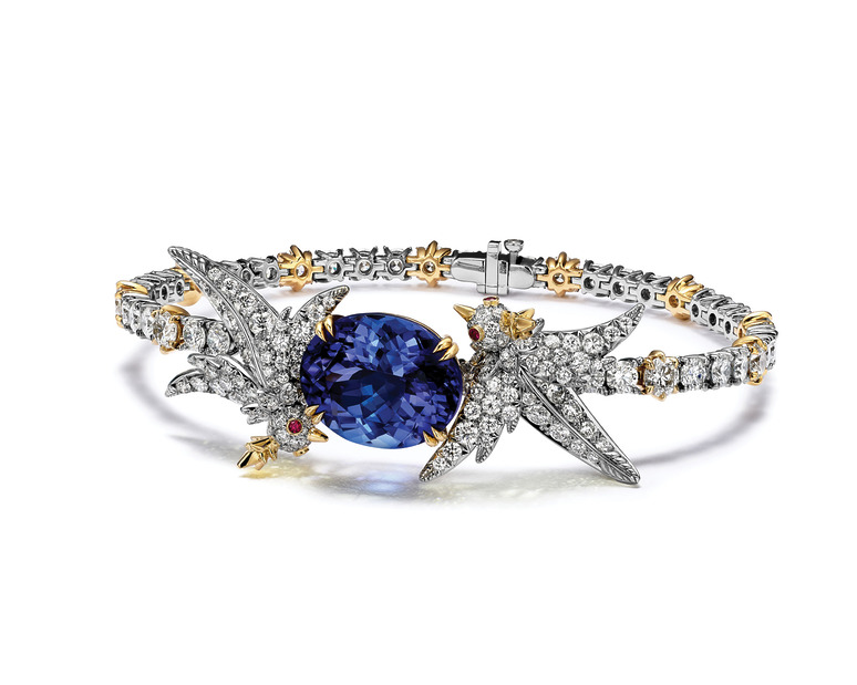 Elegant gemstone bracelet with intricate silver and gold details featuring a large blue gem at the center.