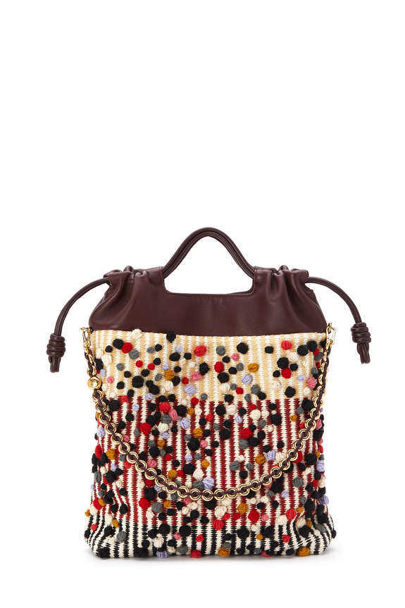 Colorful woven handbag with leather handles and gold chain strap, featuring a red, black, and white abstract pattern.