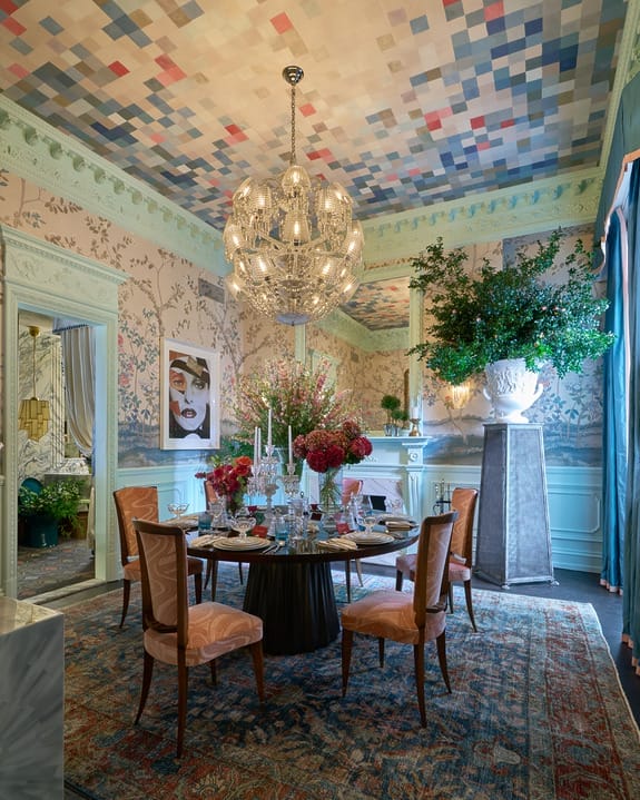 Luxurious dining room with elegant furniture, decorative ceiling, grand chandelier, and vibrant floral arrangements.